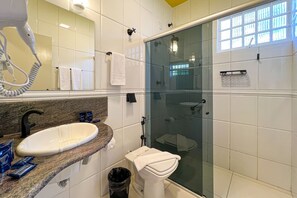 Et badeværelse med håndvask, spejl og brusekabine.