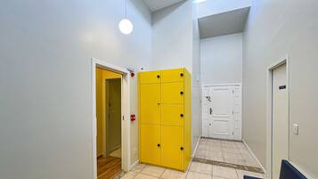 Un couloir avec un meuble de rangement jaune, une porte blanche et un banc bleu.