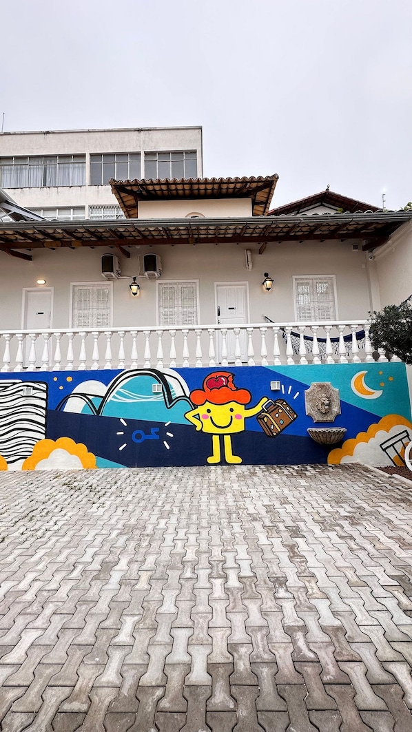 A building with a tiled roof and a mural on the wall depicting a cartoon character. - Casa Hosting (Belo Horizonte)