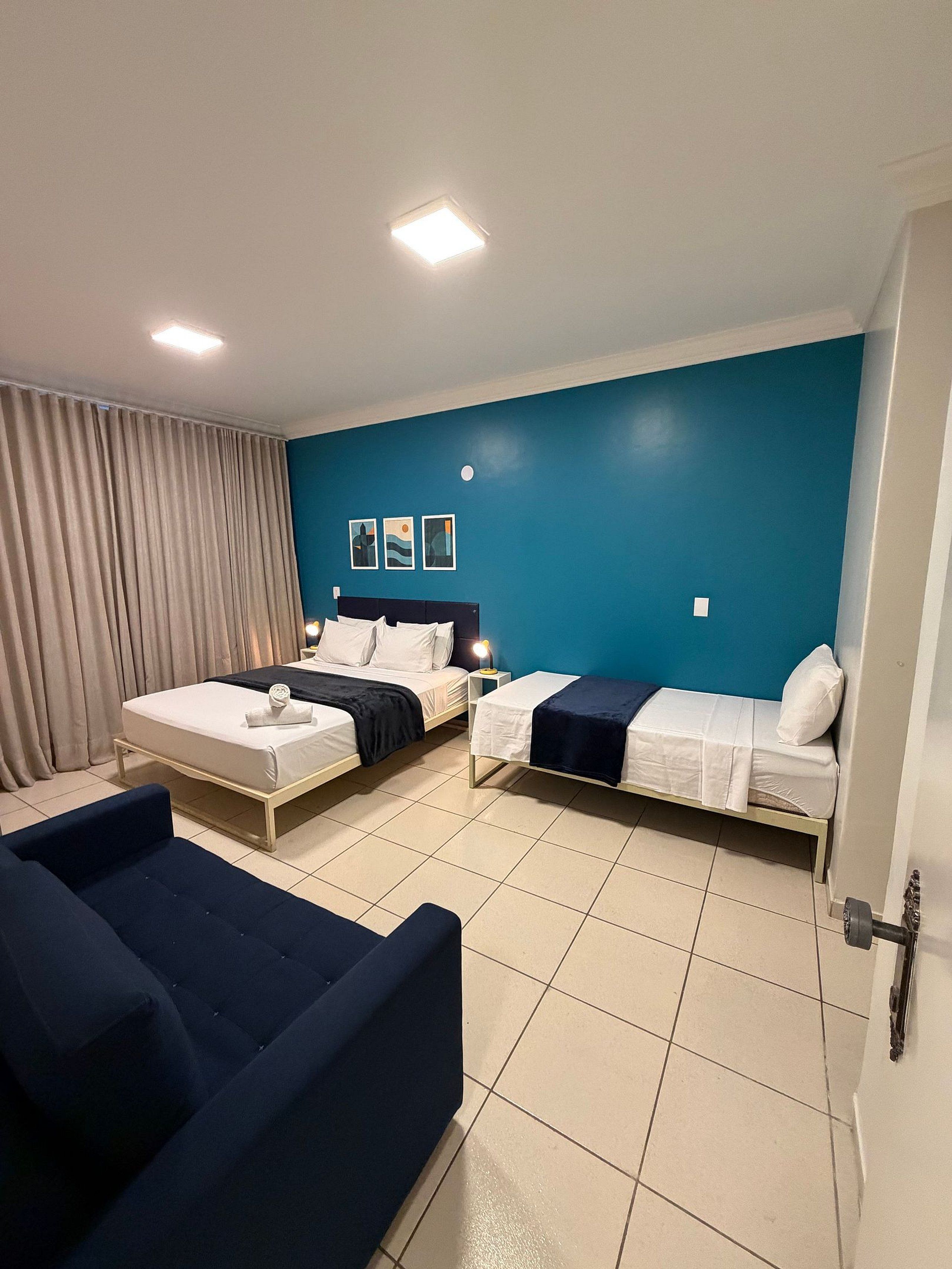 A hotel room with two beds, a sofa, and a curtain.