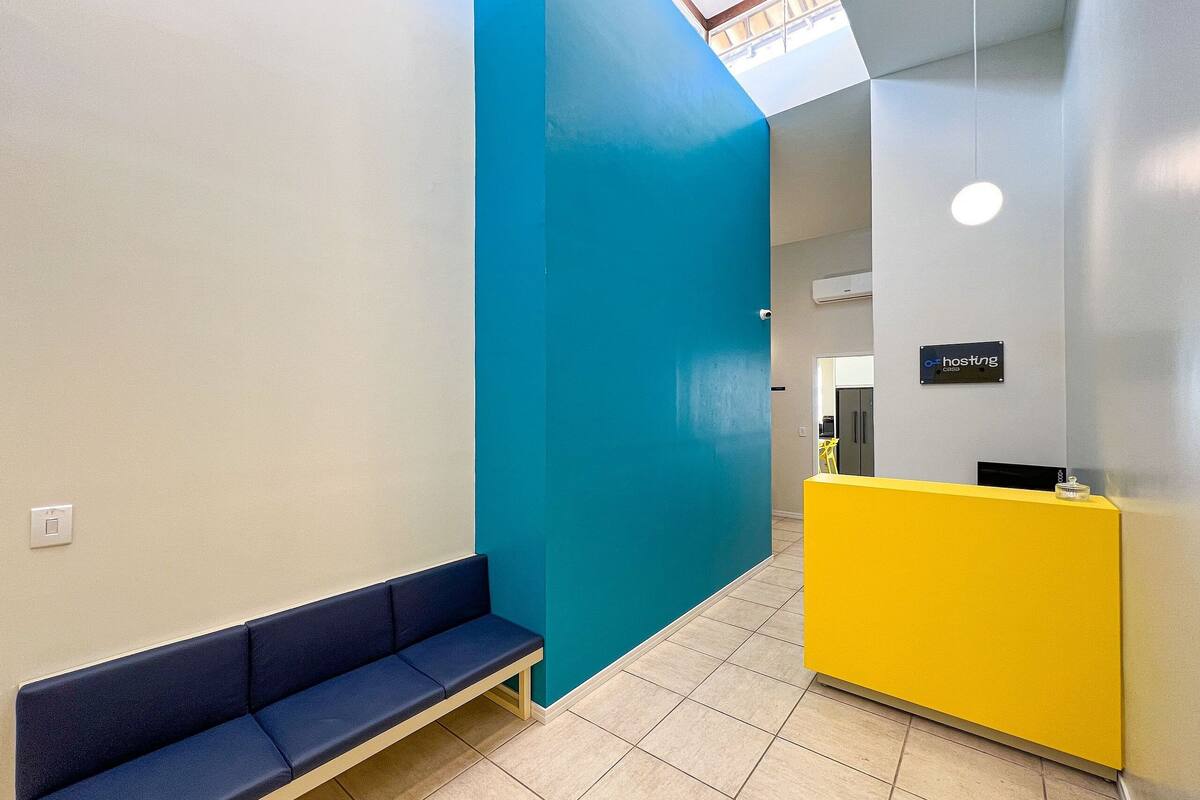 A reception area with a blue bench, a yellow counter, and a sign that reads "hosting."