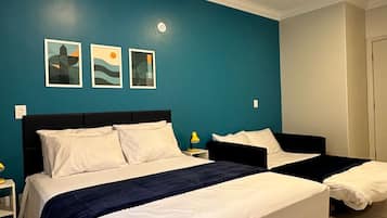A hotel room with two beds, a teal accent wall, and artwork.