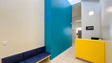 Un área de recepción con un banco azul, una barra amarilla y un letrero que dice "hosting".