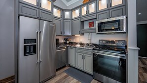 Une cuisine moderne avec des meubles de couleur grise, des appareils en acier inoxydable et un four à micro-ondes encastré.