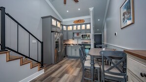 Une cuisine avec des meubles gris, des appareils électroménagers en acier inoxydable et un escalier en bois.