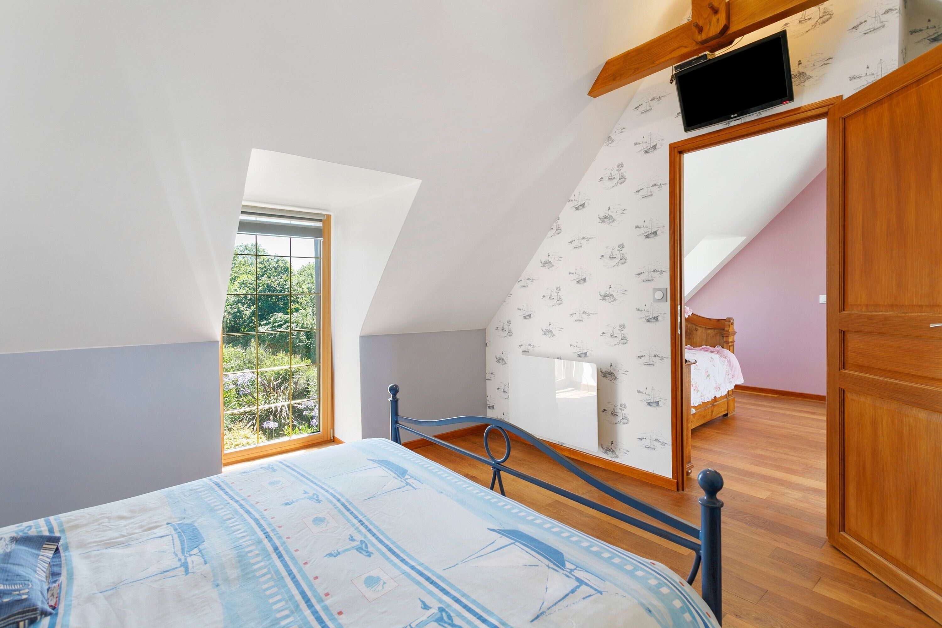 Un dormitorio con una cama, una ventana, un televisor y un armario.