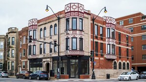 A corner building with a prominent entrance, large windows, and a fire escape. - Logan Square SRO Hotel (Chicago)