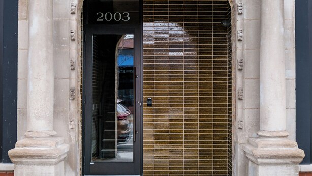 A building entrance with a large arched doorway, columns, and a sign reading "2003". - Logan Square SRO Hotel (Chicago)