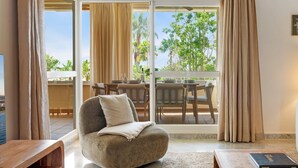 A modern living room with a sofa, a coffee table, and a dining area with a table and chairs.