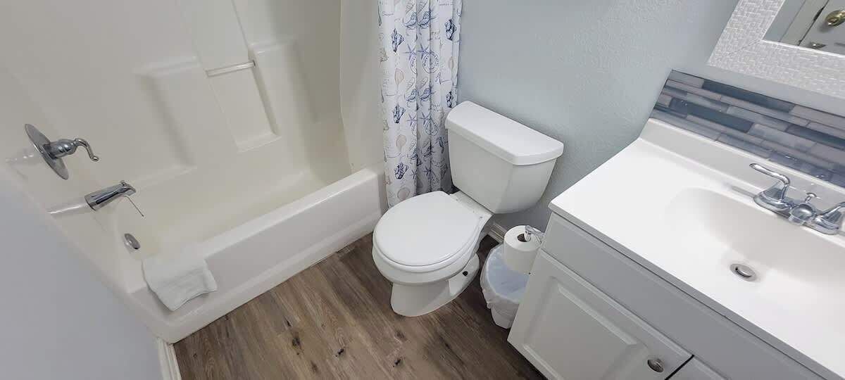 Een badkamer met een wit toilet, een badkuip en een wastafel met een spiegel erboven.