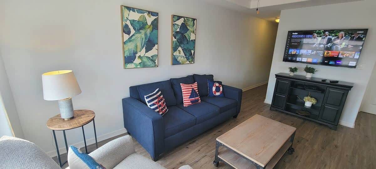 A living room with a blue sofa, a coffee table, a TV, and artwork on the wall.
