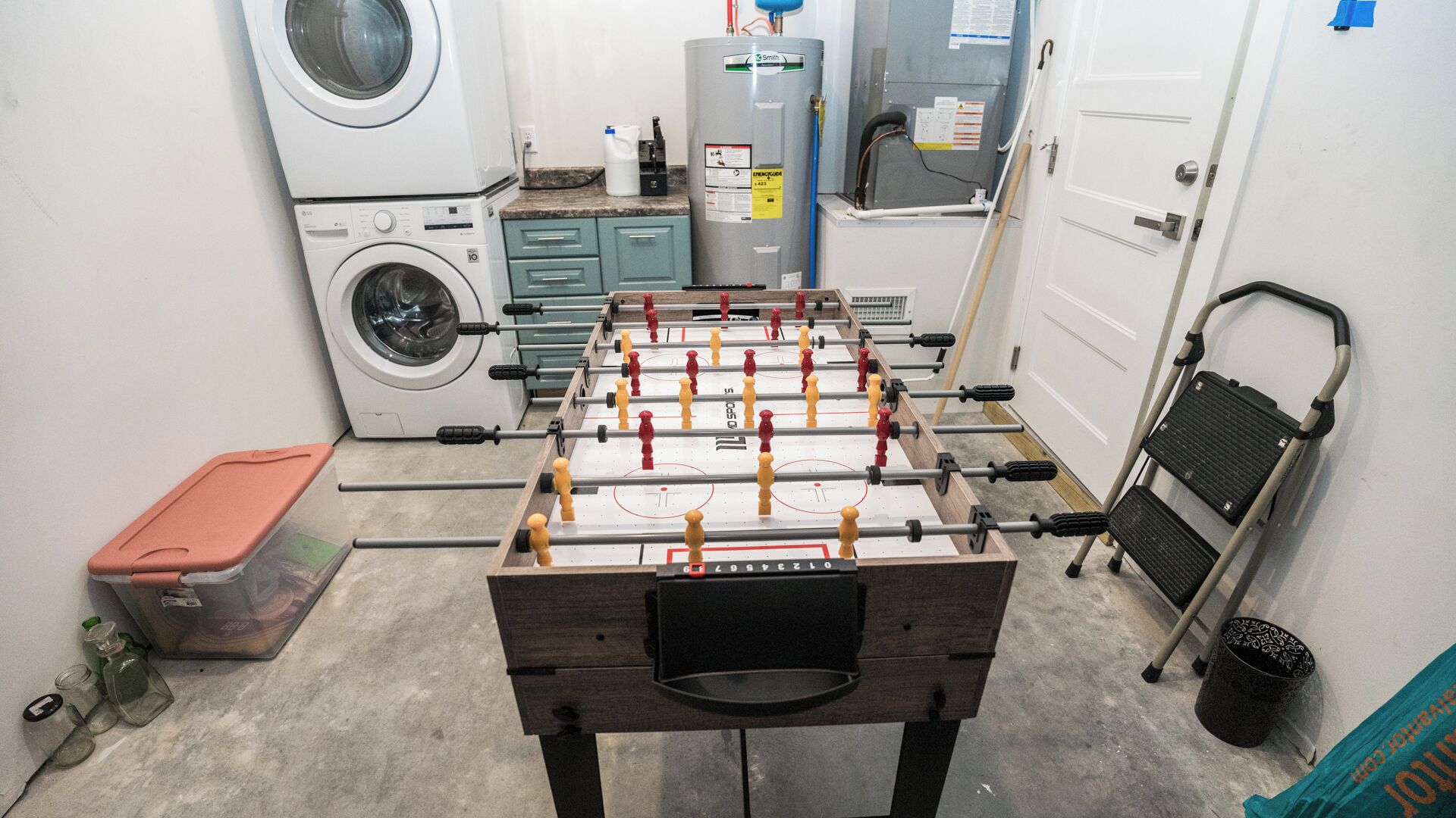 Ein Zimmer mit Kicker, Waschmaschine und Heizung.