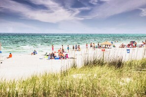 A beach with people sunbathing and swimming, a beach umbrella, and a lifeguard tower. - Mins Walk to Laguna Beach! King Suite, BBQ, Private Patio & Free parking (Panama City Beach)