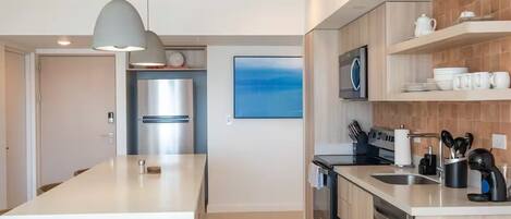 Een moderne keuken met een centraal eiland, roestvrijstalen apparatuur en houten kastjes.