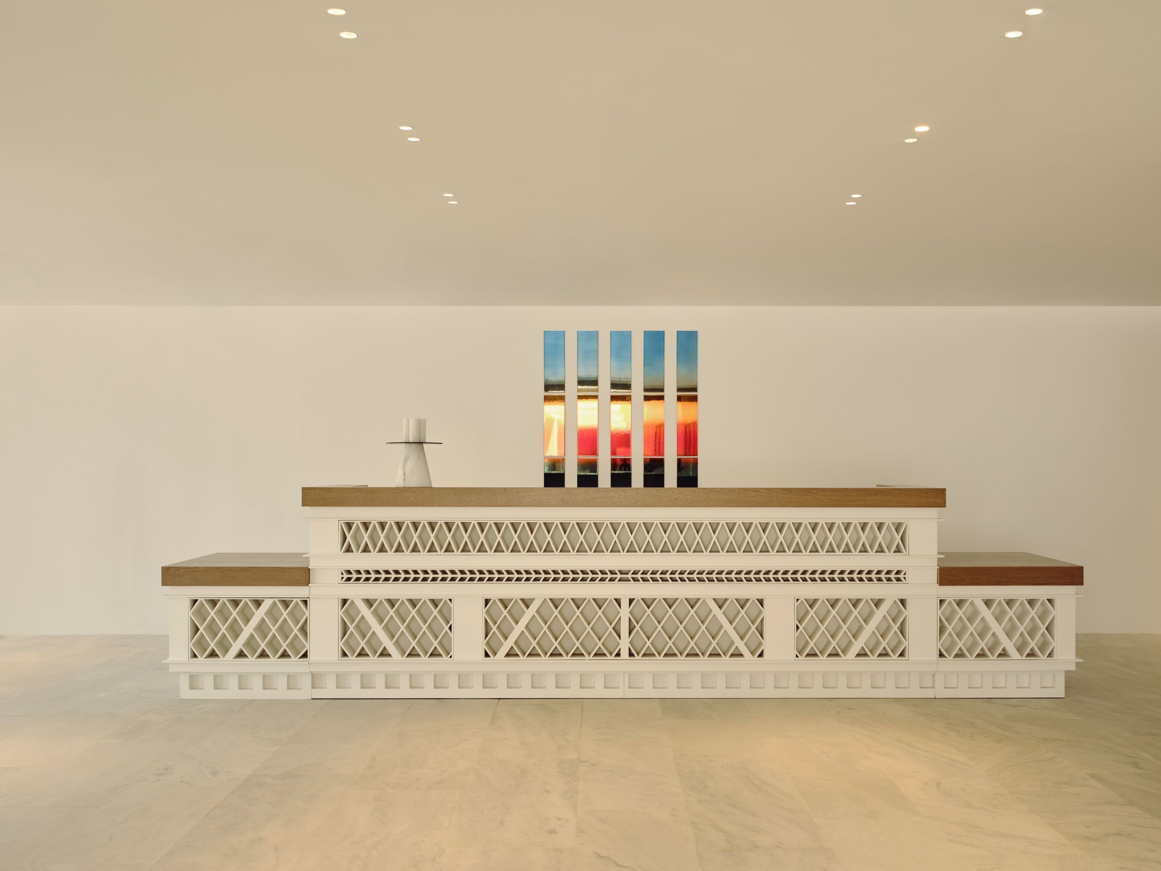A reception desk with a modern design, a wall-mounted artwork, and a simple, clean floor.
