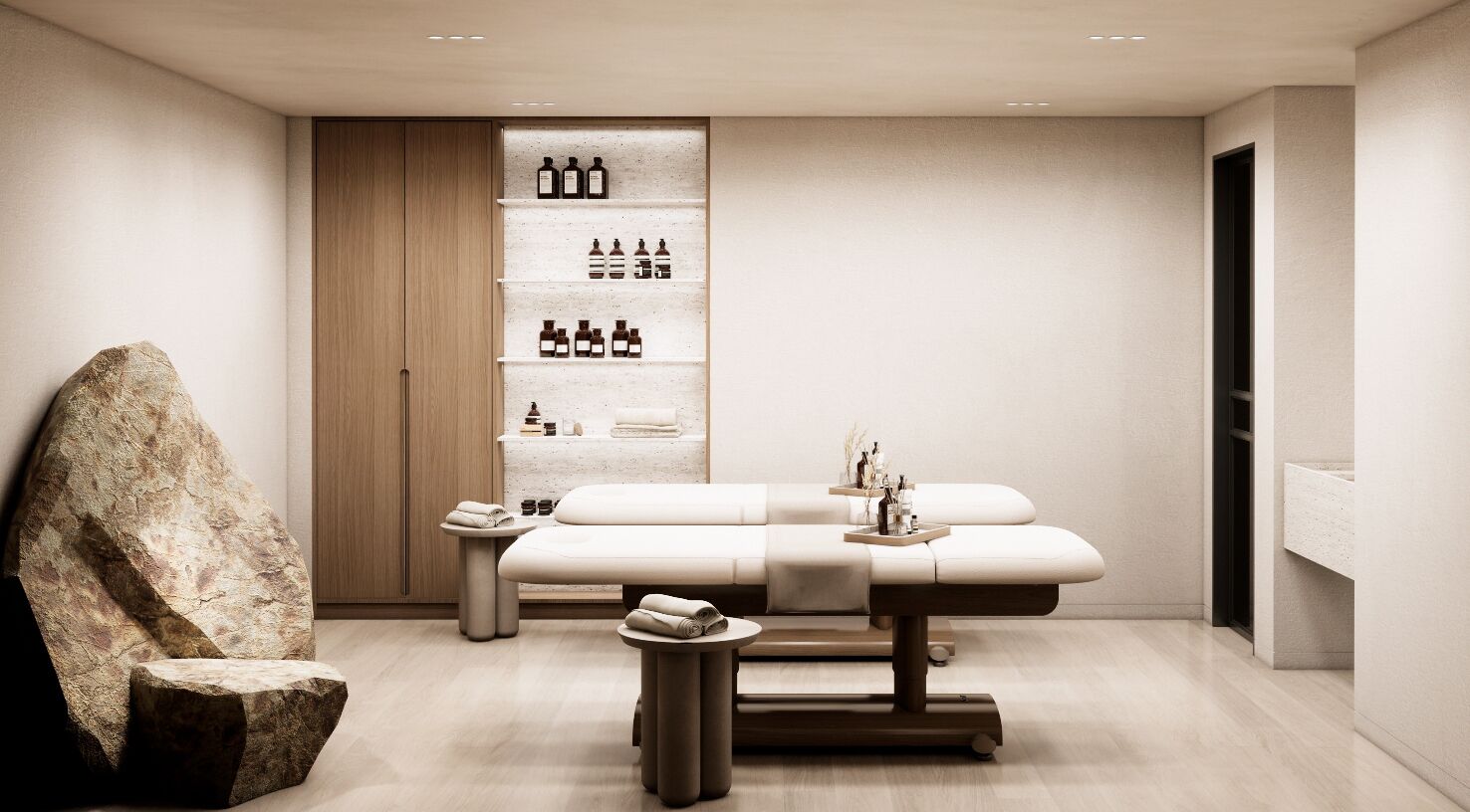 A modern spa room with a massage table, a large rock sculpture, and a shelf with bottles.
