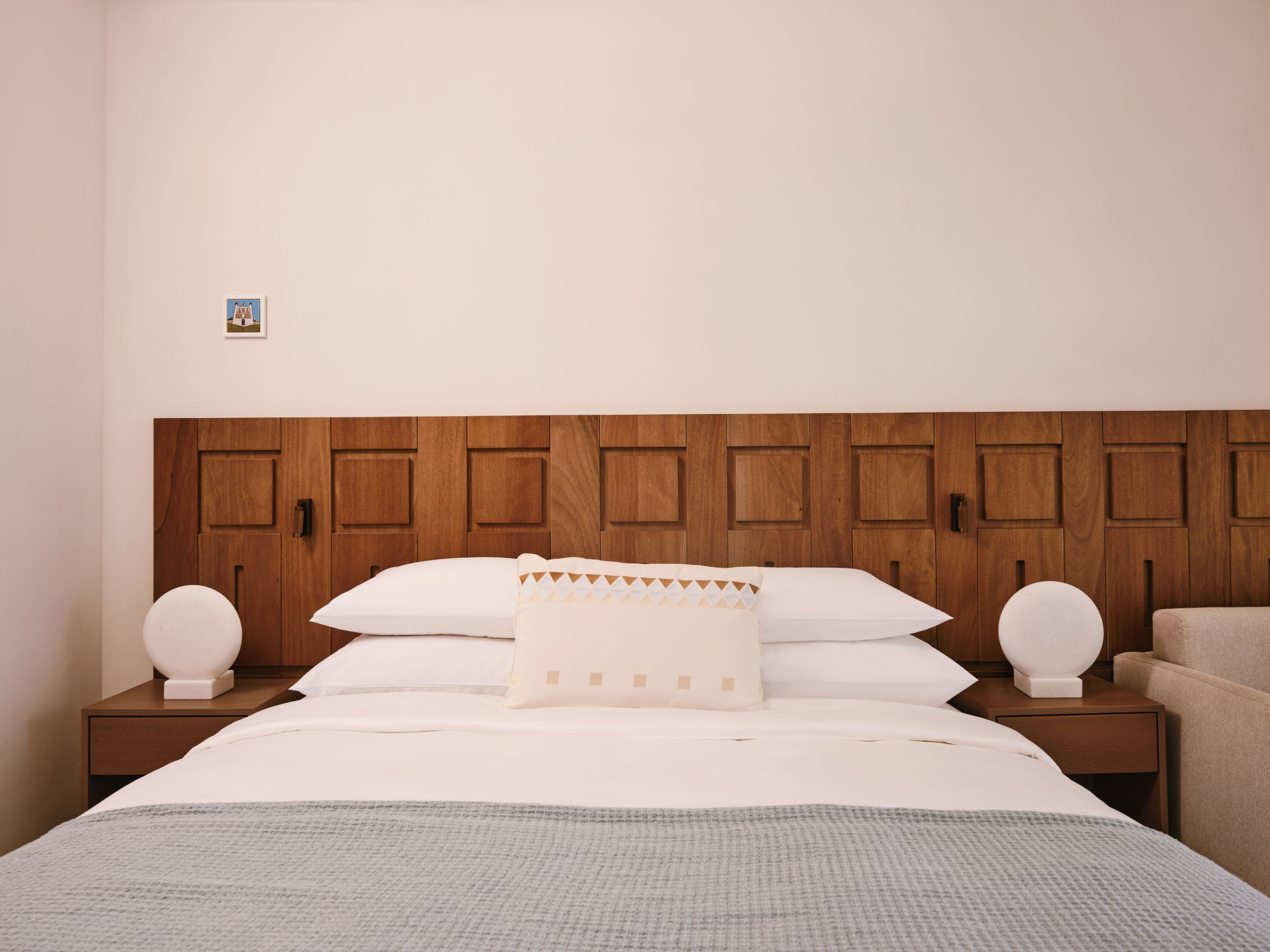 A neatly made bed with a headboard, two bedside tables, and a chair.