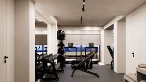 Un gimnàs modern amb equipaments d'exercici, una banca i vistes a l'oceà a través de grans finestres.