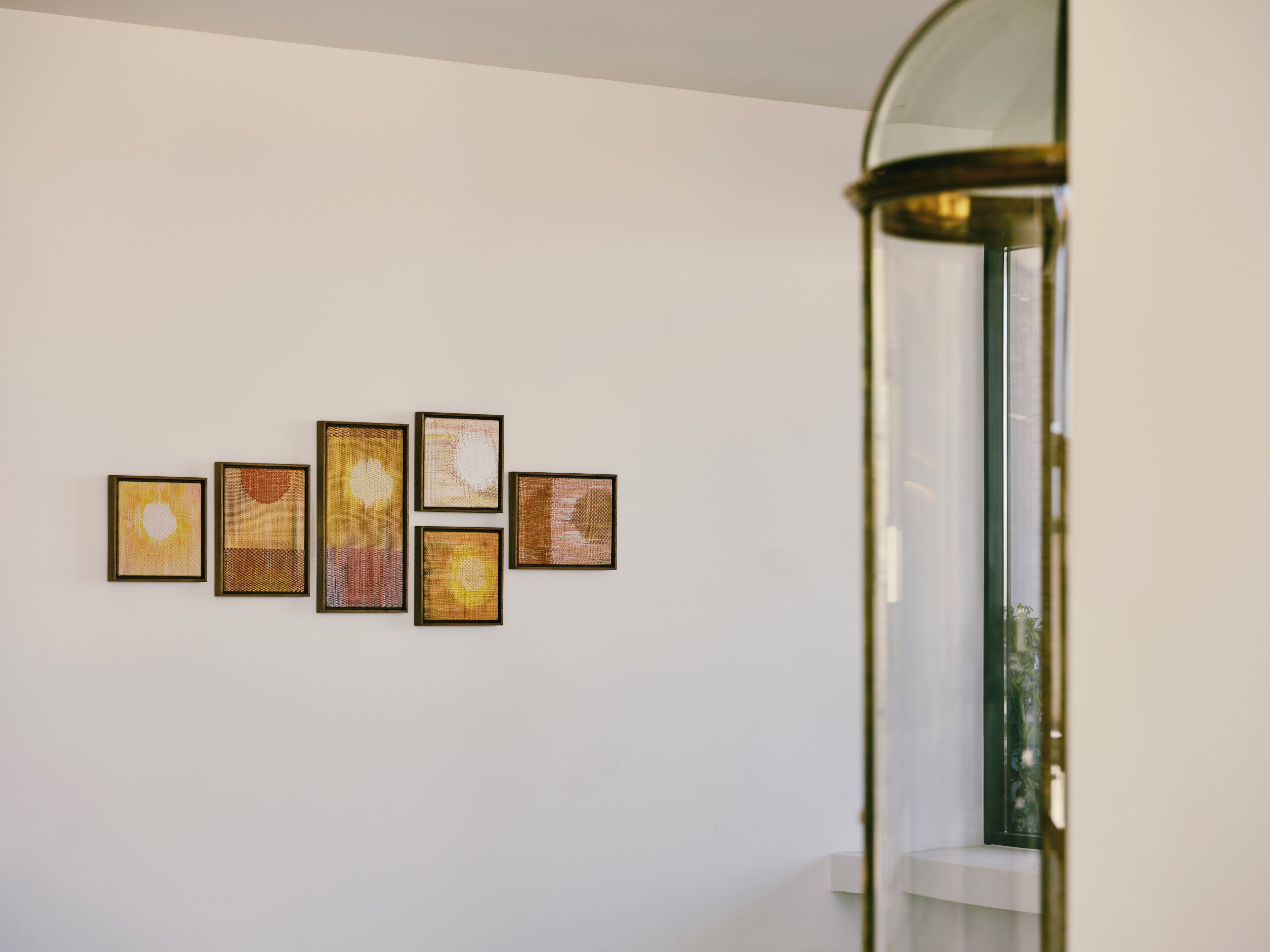 A wall with five framed artworks.
