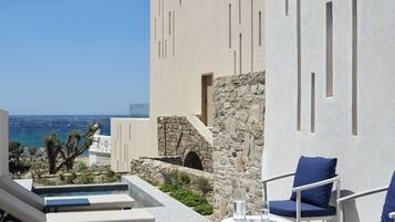 A poolside area with lounge chairs, a small table, and a view of the sea.