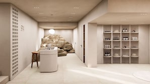 Zona d'spa amb paret de pedra, taulell de recepció i prestatges amb productes d'spa.