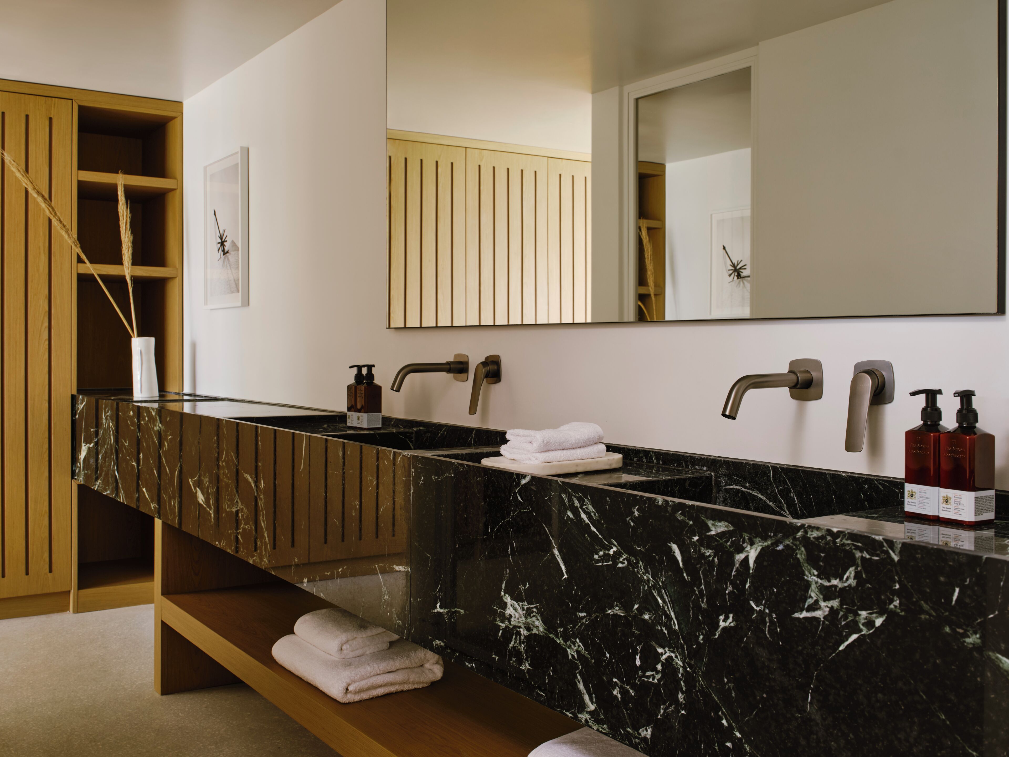 A bathroom with a black marble sink, wooden shelves, and a large mirror.