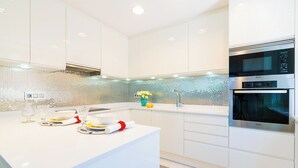 Una cocina moderna con armarios blancos, una isla grande y un horno empotrado.