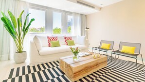 Un salón moderno con un sofá blanco, una mesa de centro de madera y una alfombra a rayas blancas y negras.