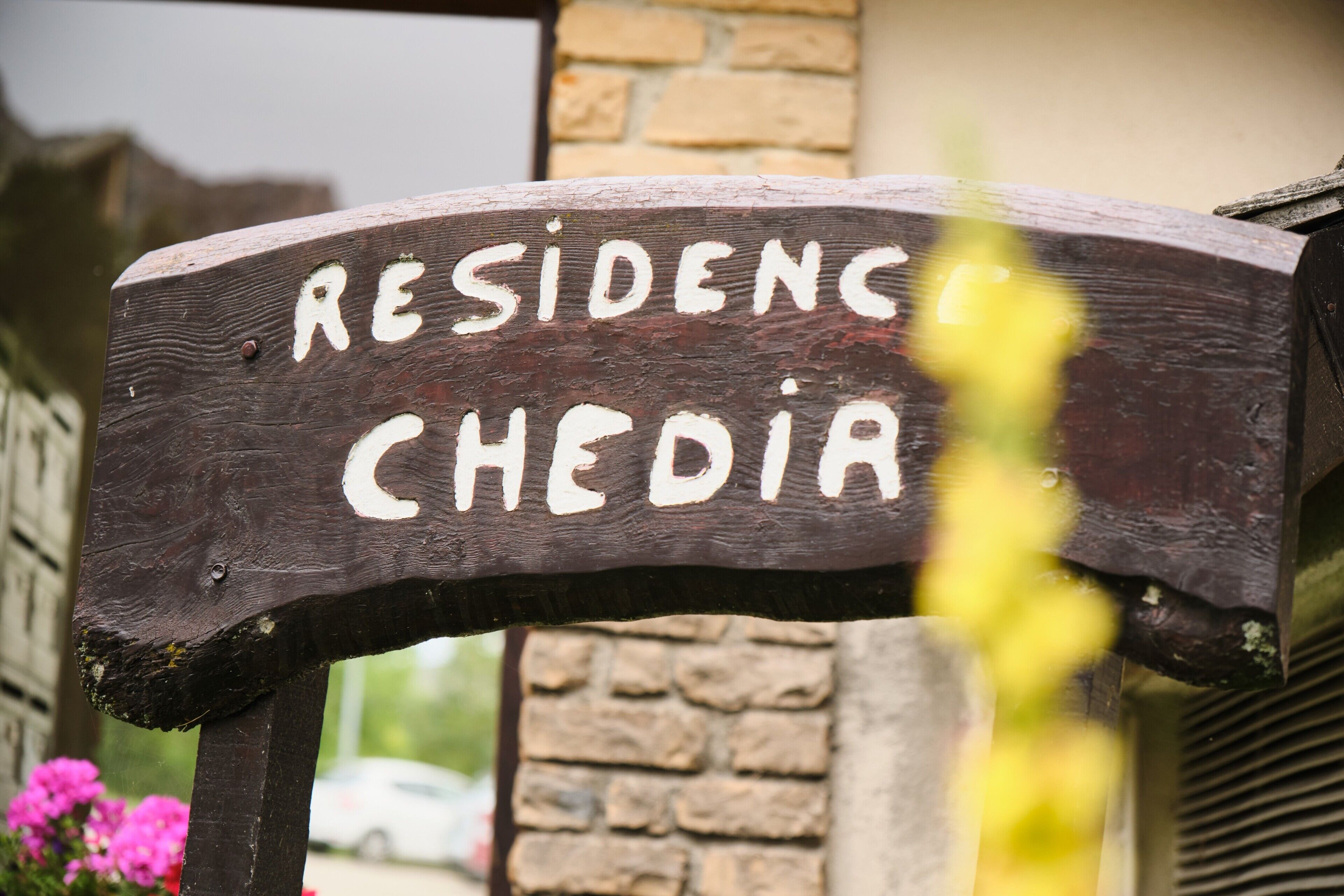 A wooden sign with the text 'RESIDENCE CHEDIA' indicating a location.