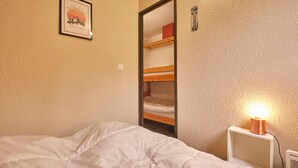 A bedroom with a bunk bed, a bedside lamp, and a framed picture on the wall.
