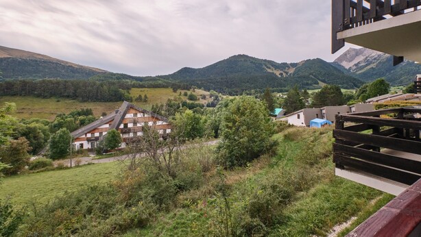A mountainous landscape with a house and a wooden deck.