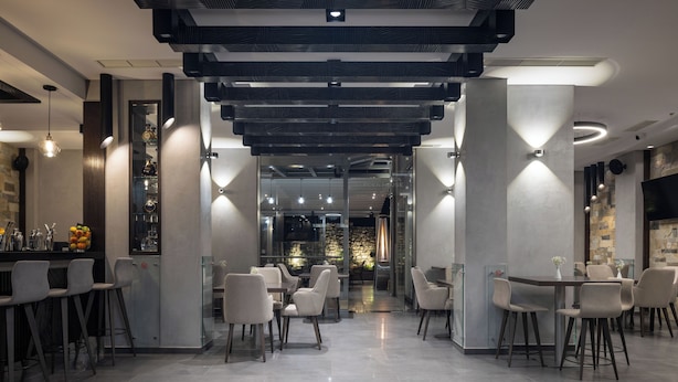 Un restaurante moderno con zona de bar, diferentes disposiciones de asientos y vistas a la cocina.
