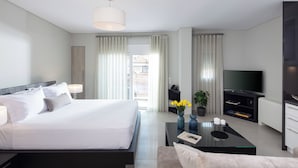 Una habitación de hotel moderna con una cama grande, un televisor de pantalla plana, una mesa de centro y vistas a la ciudad a través del ventanal.