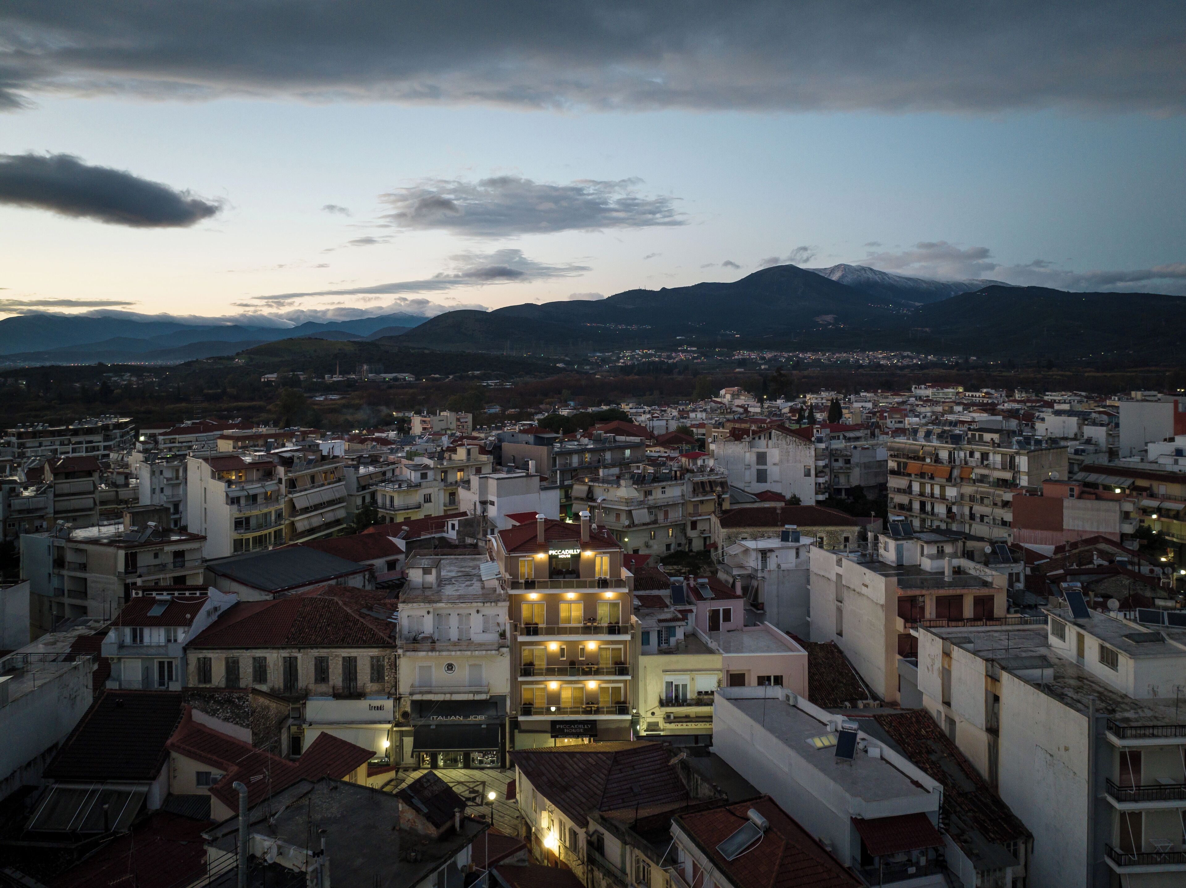 Una zona urbana densamente poblada con edificios, algunos con balcones, y montañas al fondo.