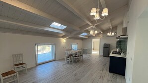 Un espacio habitable amplio con una mesa de comedor, sillas, una cocina y un tragaluz.