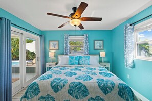 Une chambre à coucher avec un lit, un ventilateur de plafond, une fenêtre et une vue sur l’extérieur.