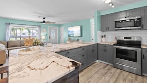 A modern kitchen with grey cabinets, a marble countertop, and stainless steel appliances. - Family Fun Getaway w/Pool, Game Room, Shuffleboard (Largo)