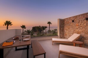 Eine Terrasse mit Esstisch, Lounge-Möbeln und einer Steinmauer.