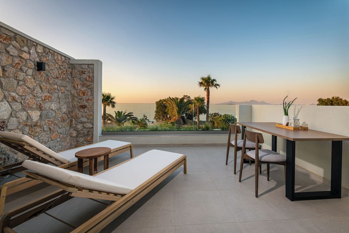 Ein Balkon mit Steinmauer, Liegestühlen, einem Tisch und Stühlen.