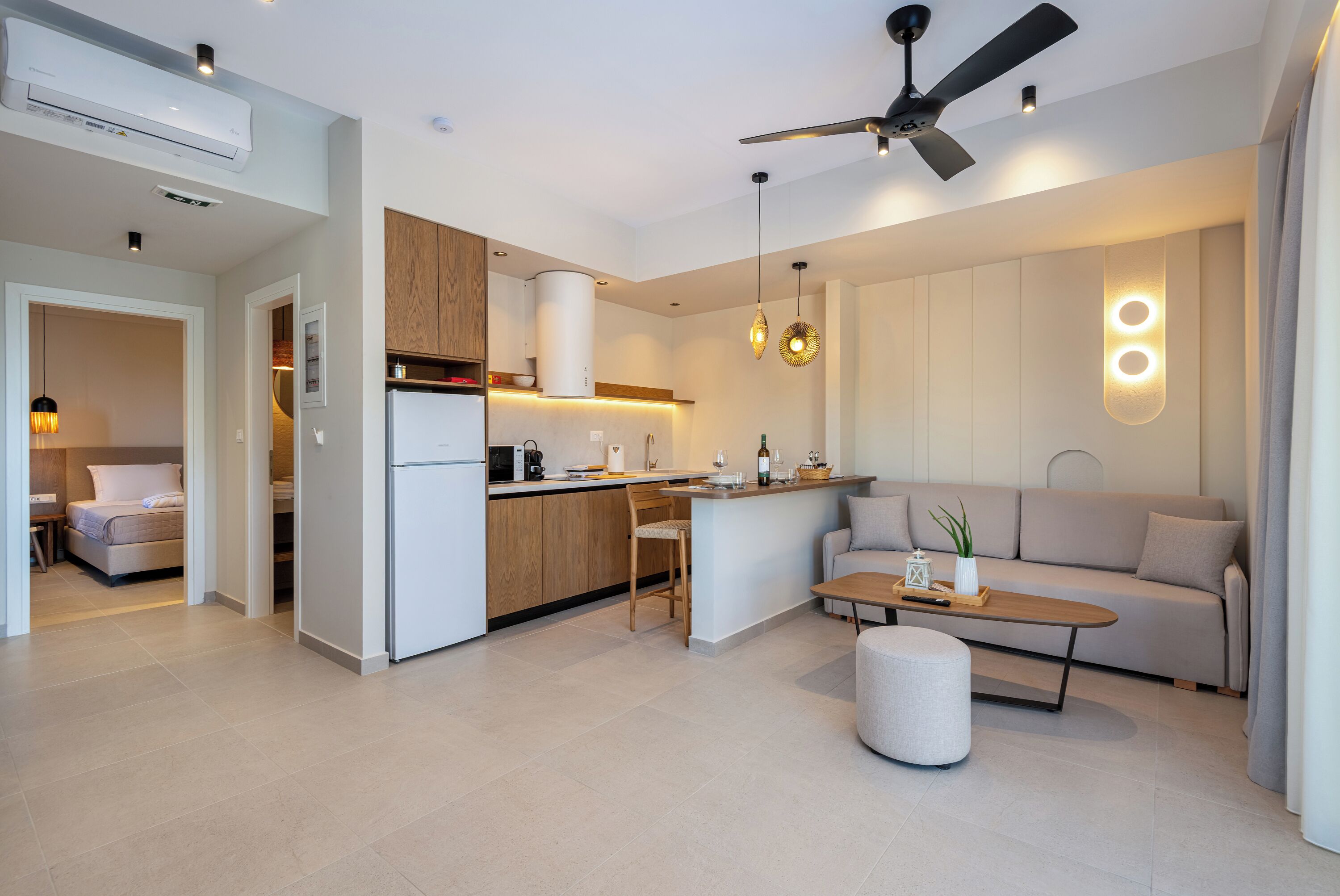 A modern kitchen with a central island, a dining area with a sofa and coffee table, and a ceiling fan.