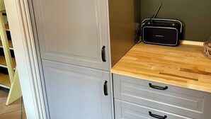 Cuina amb armaris grisos, taulell de fusta i un aparell de ràdio.