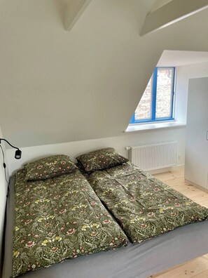A bedroom with a sloped ceiling, a window with blue trim, and a radiator.