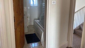 A narrow hallway leading to a bathroom with a bathtub, a small window, and a door. - Pet Friendly, Top Floor Apt w/ Sea View, Sleeps 5 (Ramsgate)