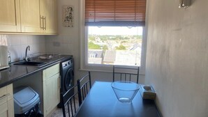 A compact kitchen with a washing machine, a sink, and a window with blinds. - Pet Friendly, Top Floor Apt w/ Sea View, Sleeps 5 (Ramsgate)