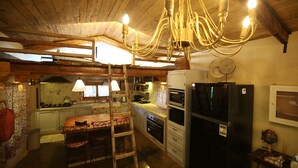 Een landelijke keuken met houten balken, een kroonluchter, een koelkast en een eettafel met stoelen.