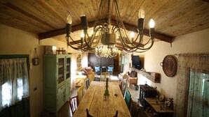 A rustic dining area with a wooden table, chairs, a chandelier, and a green cabinet.