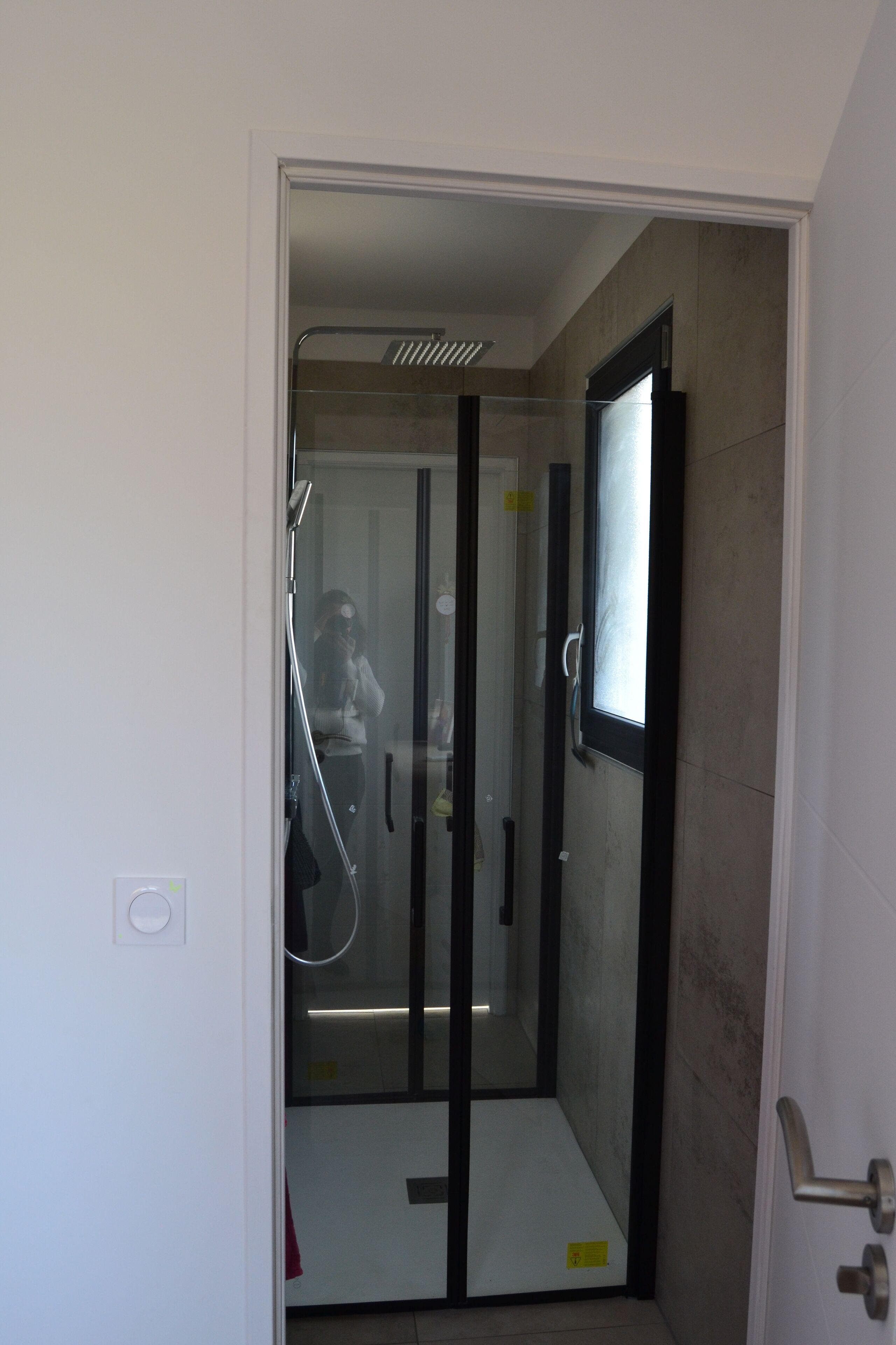 A glass-enclosed shower stall with a door, a towel rack, and a visible shower head.