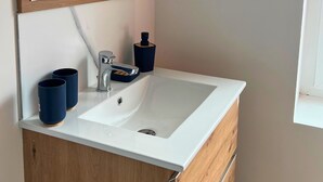 A bathroom with a white sink, wooden cabinet, and a mirror. - Apart'Moment EN GROUPE - L'Horizon Bleu (Bourbourg)