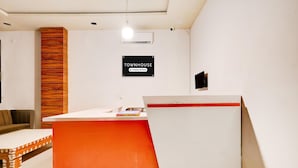 A reception area with a white desk, a red accent wall, a wooden panel, and a sign indicating the property is company-serviced.
