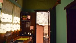 Une petite cuisine équipée d’un évier, d’une cuisinière et d’une fenêtre avec un rideau.